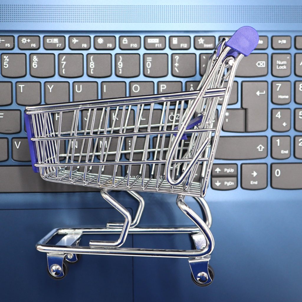 A miniature shopping cart placed on a laptop keyboard symbolizing online shopping and e-commerce.