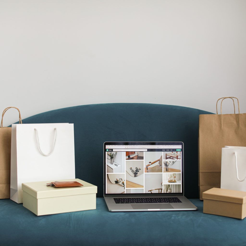 pexels photo 6956903 6956903 A laptop surrounded by shopping bags and boxes on a blue sofa, ideal for online shopping themes.